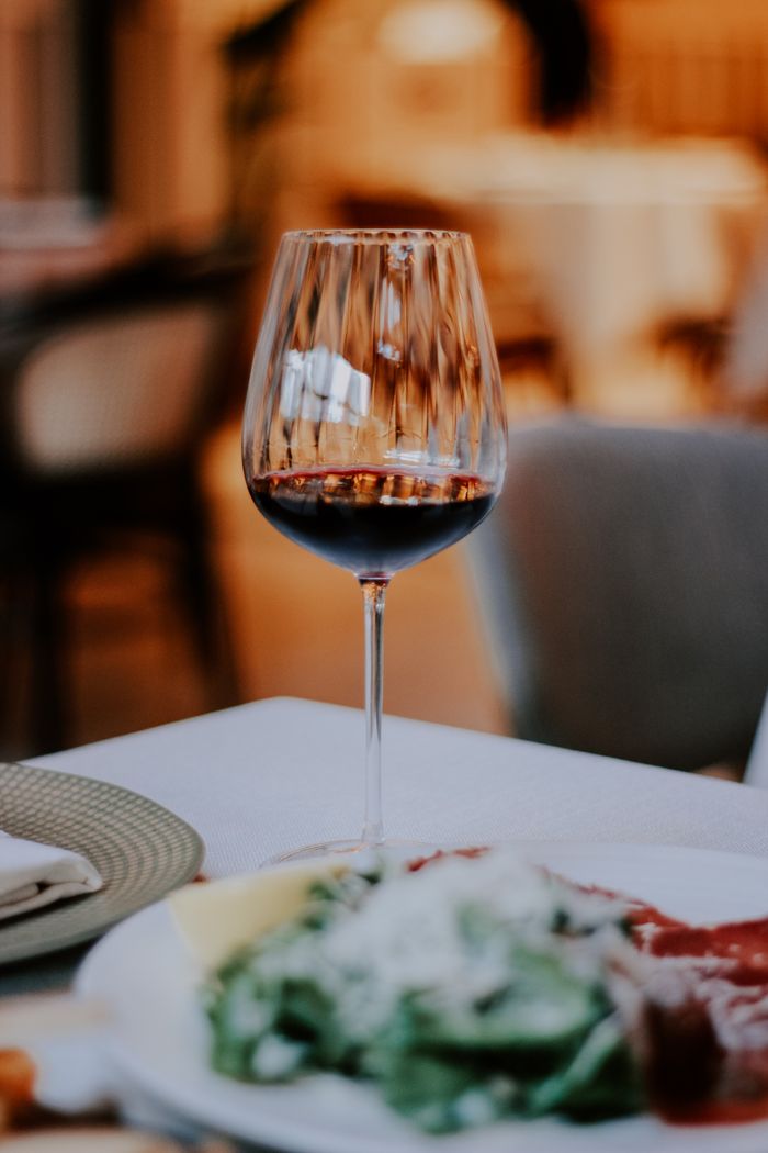 A glass of red wine elegantly set on a restaurant table with a blurred background.