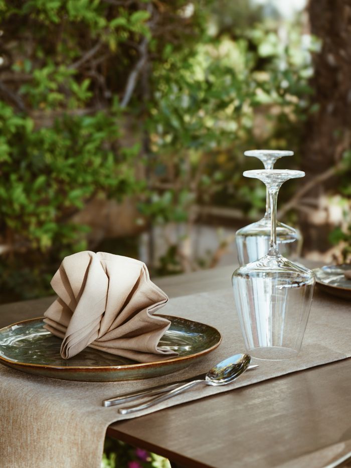 about-img Charming outdoor dining table in Durrës, Albania, with neatly arranged cutlery and glassware.
