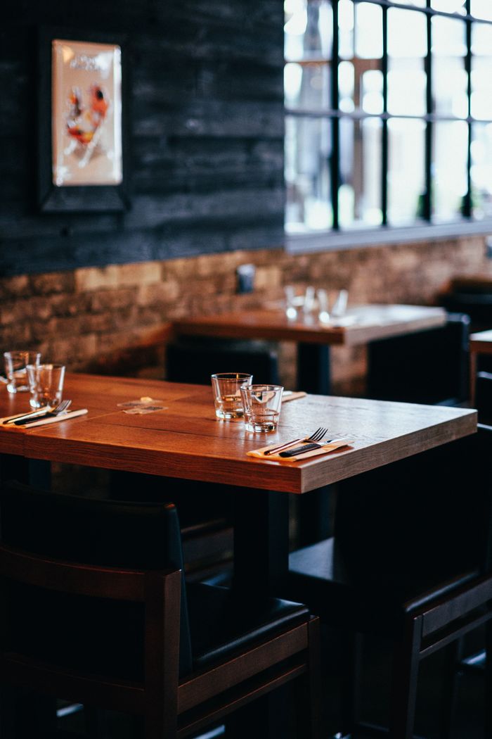 Warm and inviting restaurant interior with wooden tables and elegant glassware, perfect for dining.